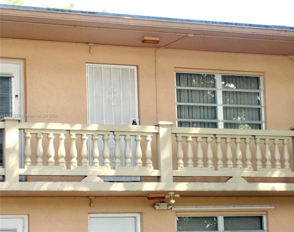 Front view of a building with a balcony and barred door.