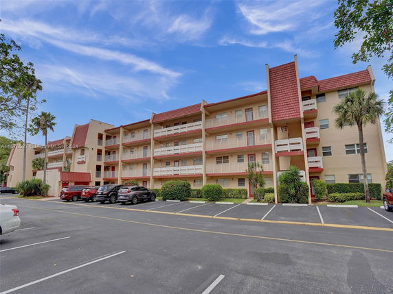 Front view of a four-story residential building with balconies and red roofing.