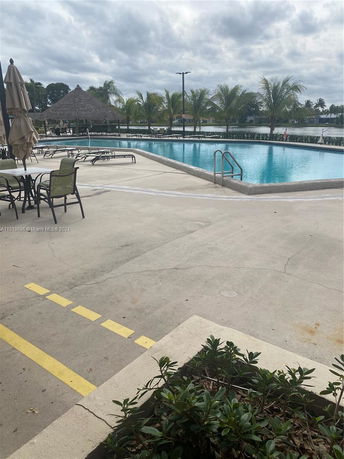 Outdoor swimming pool with seating and umbrellas nearby.