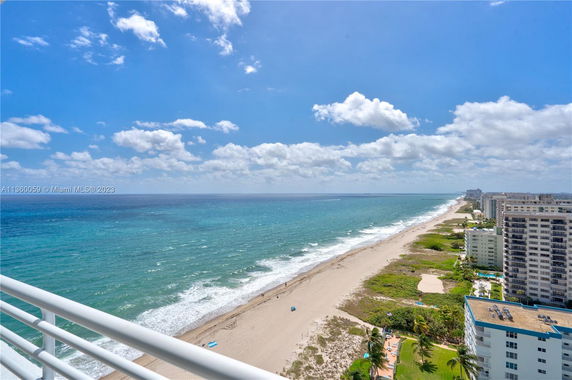 Panoramic view of a coastline with buildings along the beach, seen from a balcony.