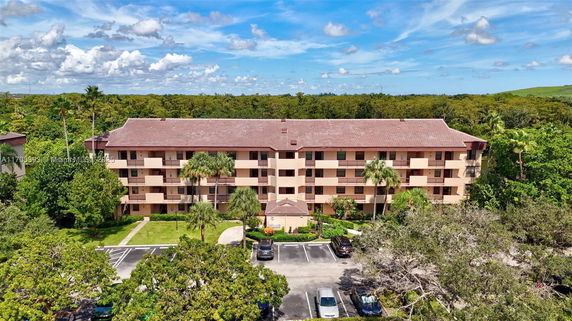 Front view of a multi-story apartment building with parking area in front.