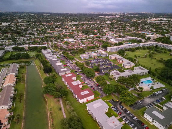 Aerial panoramic view of a residential area with multiple buildings, parking lots, and a visible waterway.