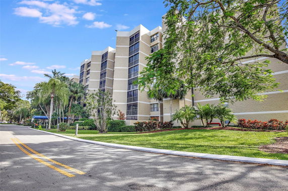 Front view of a multistory building with balconies and landscaped surroundings.