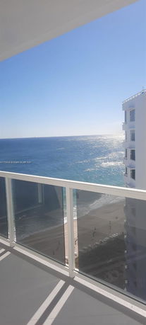 View from a building balcony overlooking the ocean and beach.
