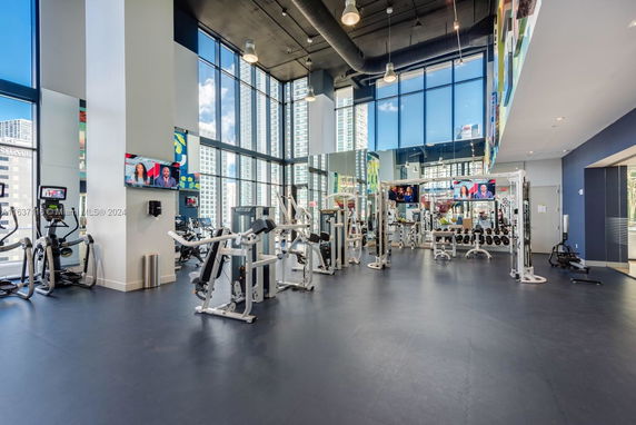 Spacious gym area with exercise equipment and large windows.