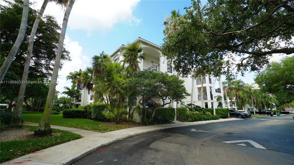 Front view of a multi-story residential building surrounded by trees and greenery.