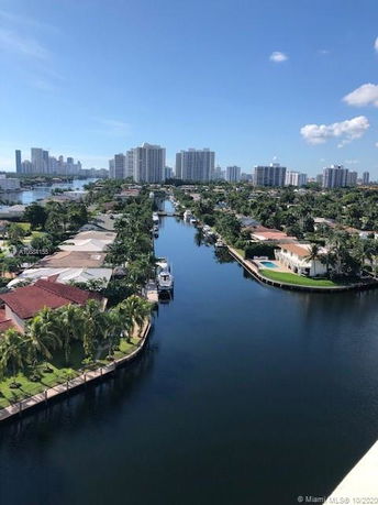 View of residential area along a waterway with city skyline in the background.
