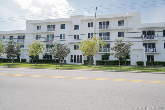 Front view of a multi-story residential building with white exterior and balconies.
