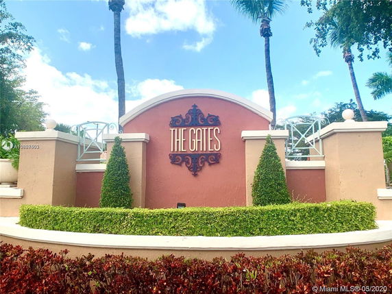 Entrance signage for a place named 'The Gates' with decorative fencing and manicured landscaping.