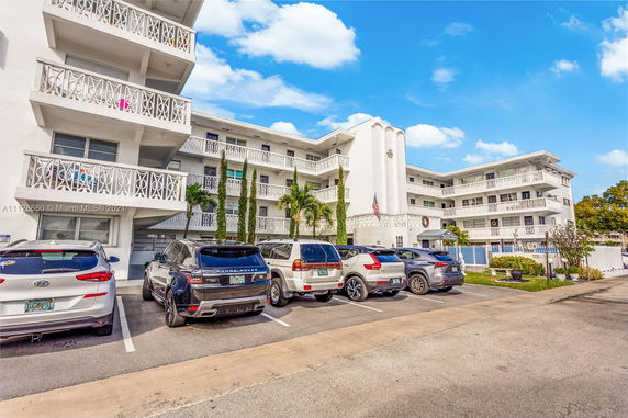 Outdoor parking area in front of a multi-story building with balconies.
