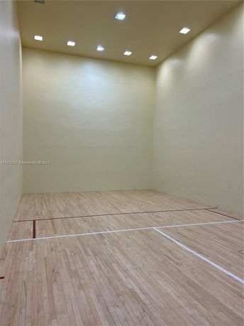 Indoor squash court with wooden flooring and high walls.