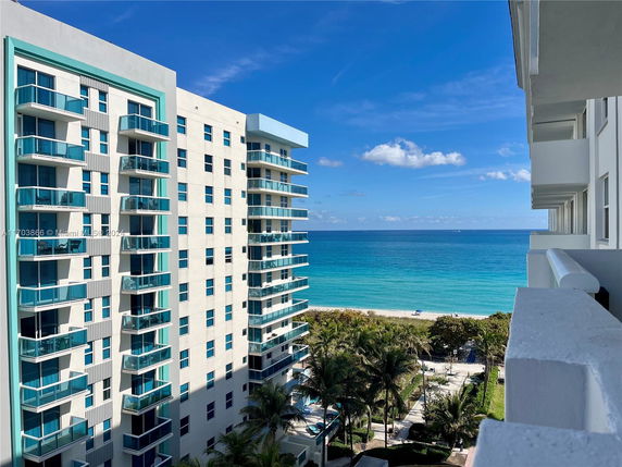 High-rise apartment building near the ocean with blue balconies.