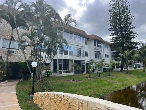 Front view of a multi-story residential building with large windows and surrounding greenery.