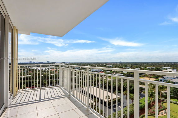 Panoramic view from a balcony overlooking a wide area with buildings and greenery.