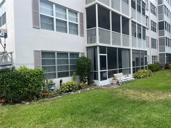 Front view of a multi-story building with screened balconies and landscaped area.