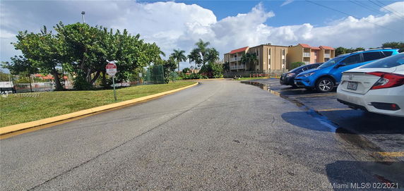 Outdoor parking area with several parked cars near a building.