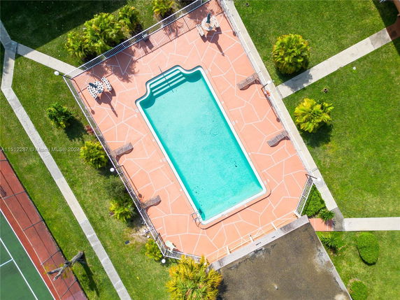 Aerial view of a rectangular swimming pool with surrounding deck chairs and umbrellas.