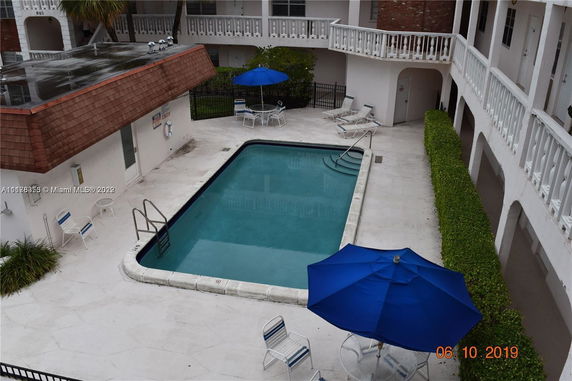 View of an outdoor swimming pool area with seating and umbrellas.