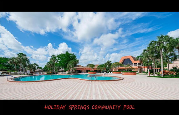 Community pool area with surrounding trees and a building in the background.