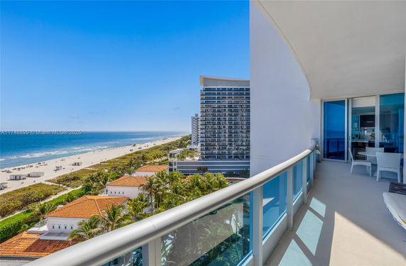 View from a building balcony overlooking a beach and ocean.