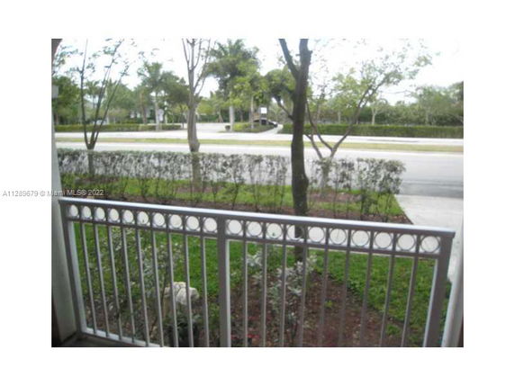 View from a balcony overlooking a street with trees and landscaping.