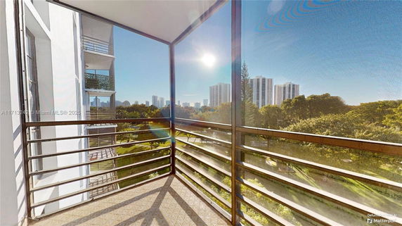 View from a balcony showing tall buildings and greenery in the distance.