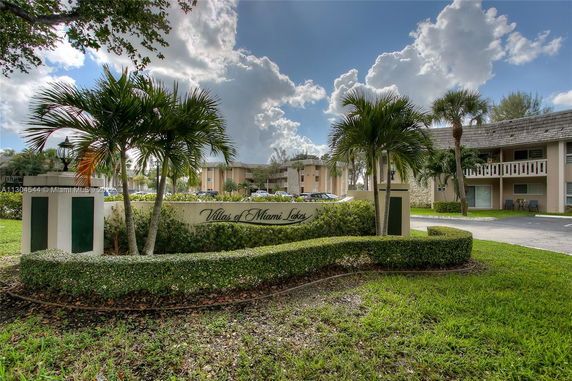 Front view of a residential complex with palm trees and signage.