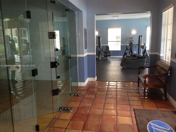 Interior view of a recreation area with gym equipment visible through glass doors.