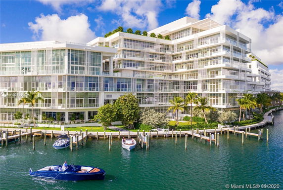 Front view of a multi-story building with large glass windows by the waterfront.
