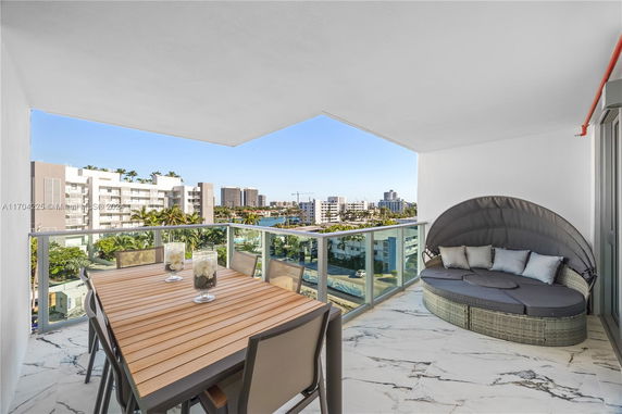 Balcony with dining table and patio seating, overlooking cityscape.
