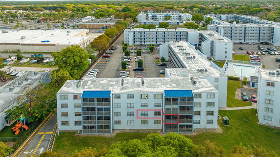 Aerial view of apartment buildings with parking lots and surrounding greenery.