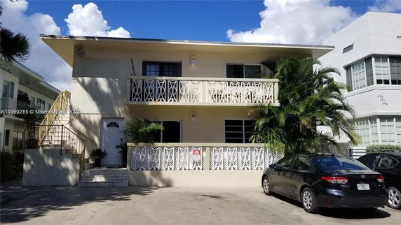 Front view of a two-story building with decorative railing and exterior staircase.