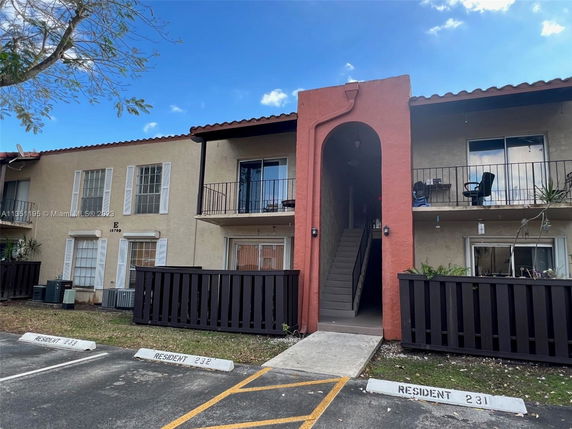 Front view of a two-story apartment building with balconies and a central staircase entrance.