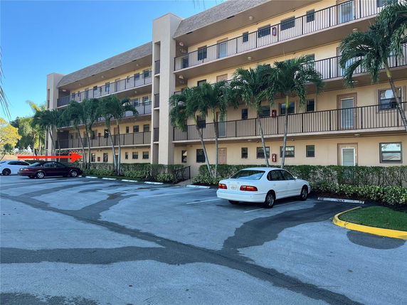 Front view of a multi-story building with balconies and palm trees.