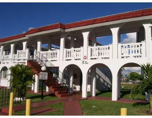 Front view of a two-story building with arched balconies and red roof tiles.