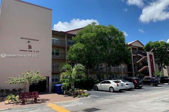 Front view of a multi-story residential building with parking area.