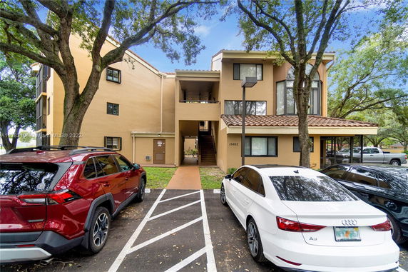 Front view of a multi-story apartment building with parked cars in front.