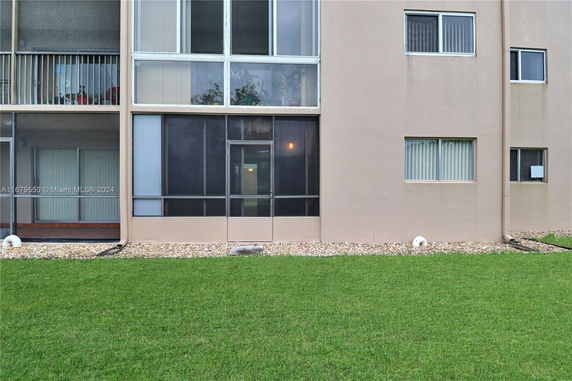 Front view of a multi-story building with screened windows and sliding glass doors.