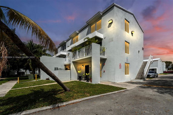 Front view of a three-story building with balconies and exterior stairs.