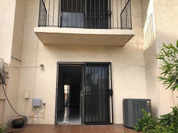 Back view of a building with a balcony and a ground-level metal door.
