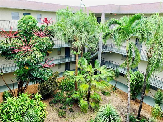 View of a building courtyard with lush tropical plants and external corridors.
