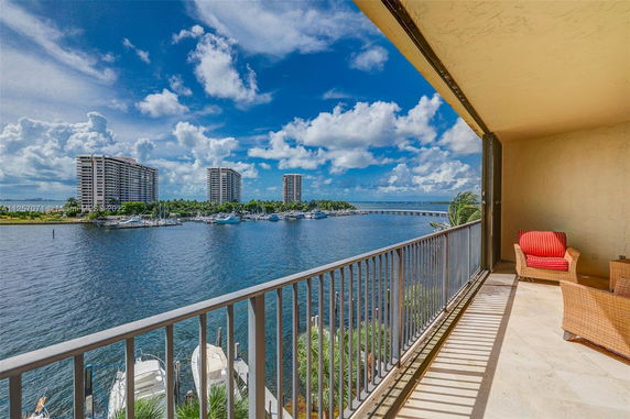 Balcony view overlooking a waterfront with high-rise buildings in the distance.
