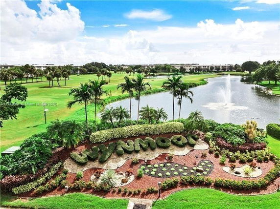 Scenic view of landscaped garden with a pond and fountain in the background.