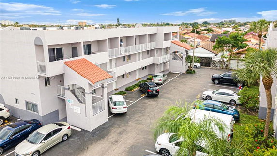 Front view of a multi-story apartment building with parking area.