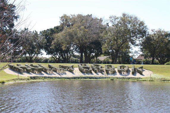 Lakeside view with shaped hedges spelling 'WOODBRIDGE' and trees in the background.