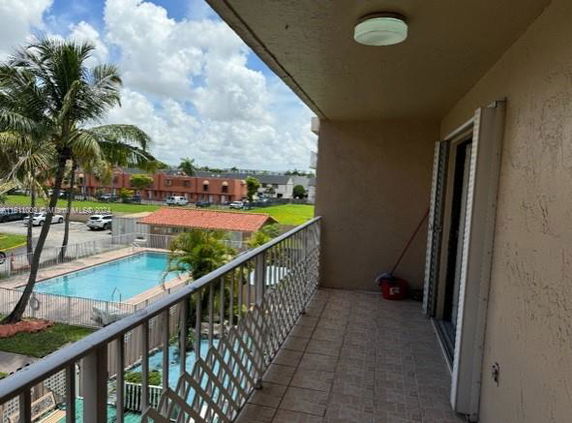View from a balcony overlooking a swimming pool in a residential area.
