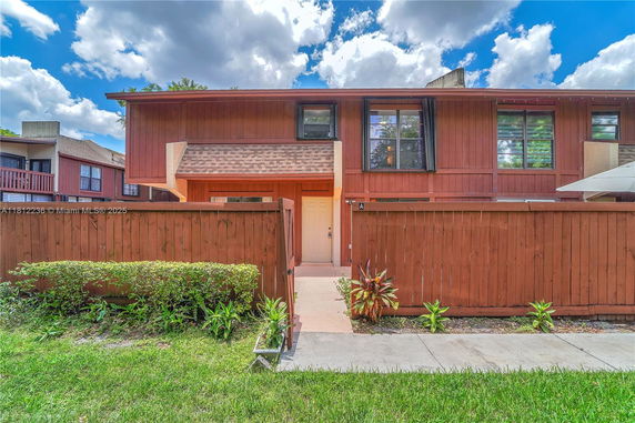 Front view of a two-story house with a wooden fence and a front entrance.