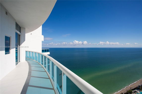 Panoramic view of the ocean from a curved balcony on a high floor.