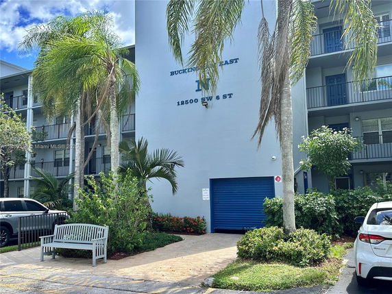 Front view of a multi-story building with balconies and a blue garage door.