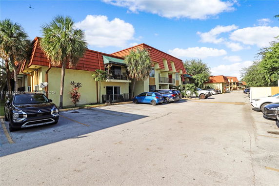 View of a residential building with parking spaces in front of it.